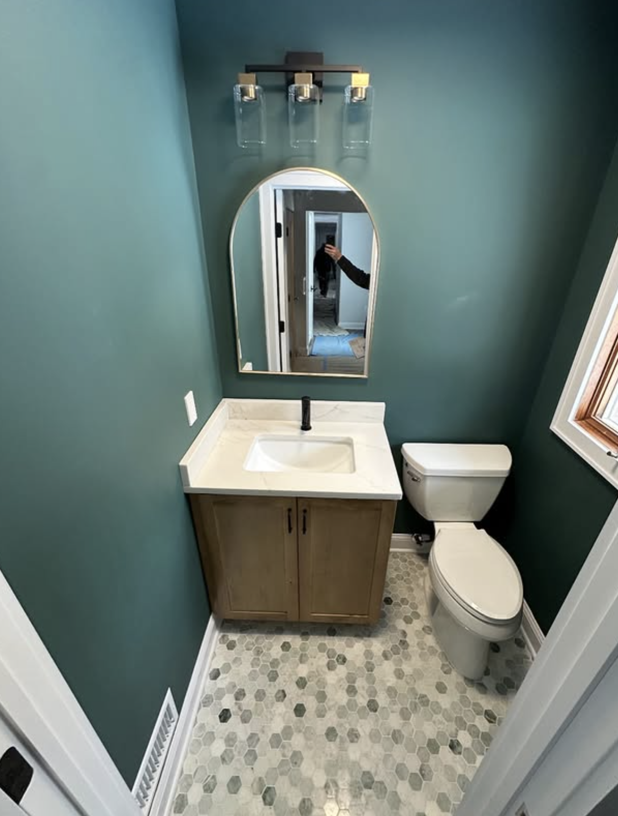 Teal powder room with arched mirror by Zollinger Construction in East Brunswick, NJ