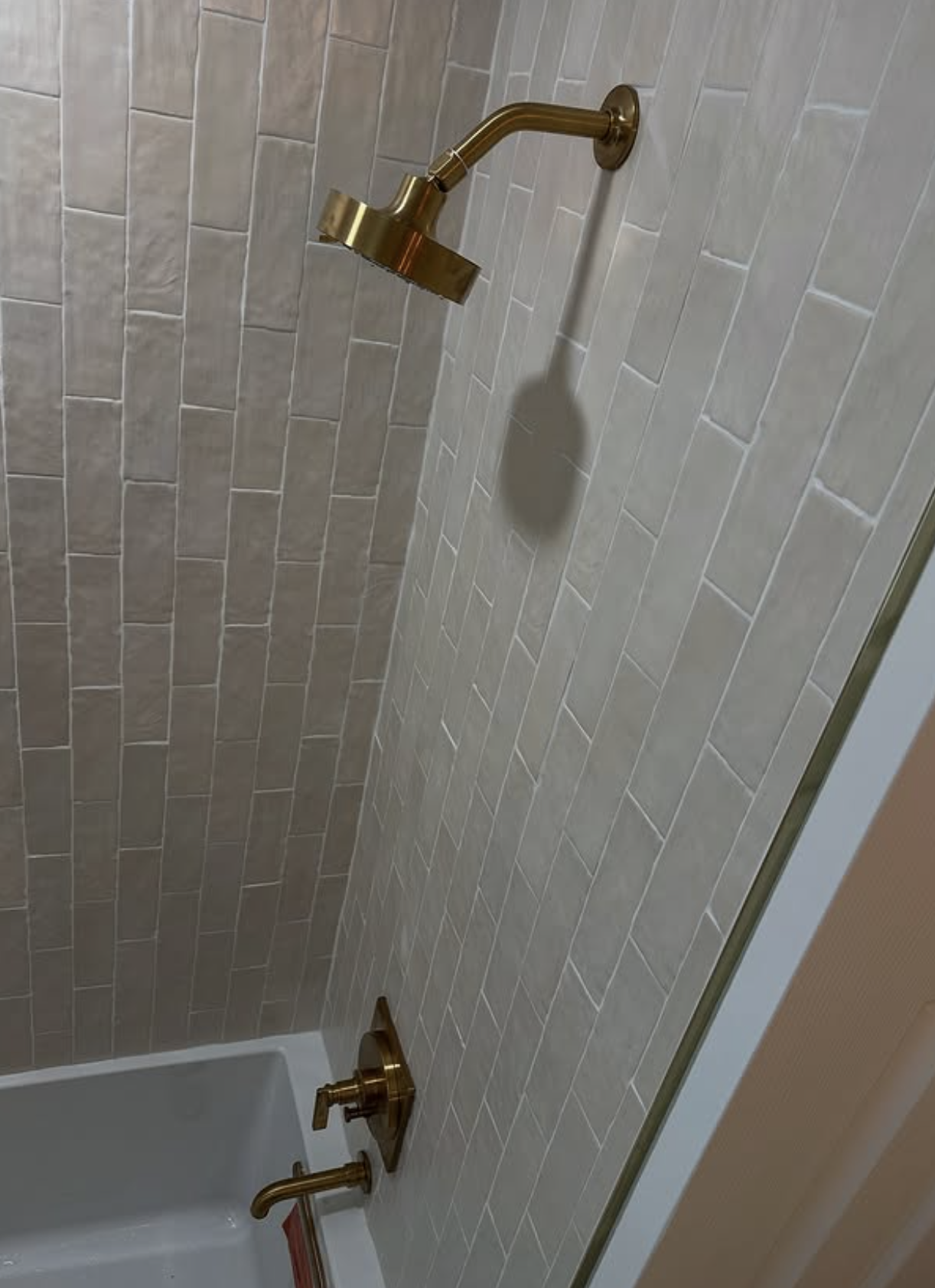 Brass shower head on stacked tile by Zollinger Construction in Aberdeen, NJ