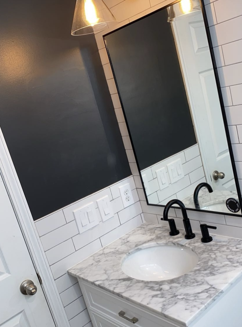 Marble vanity with black faucet and framed mirror by Zollinger Construction in Aberdeen, NJ