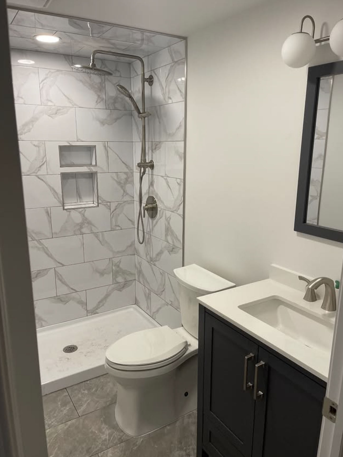 Compact bath with marble shower by Zollinger Construction in Keyport, NJ